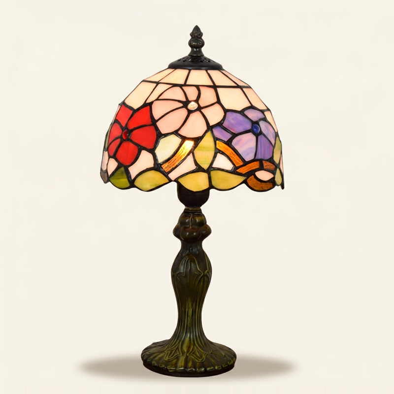 Trivelle 8 Inch Tiffany-style stained glass table lamp, lit, on a plain ivory studio background