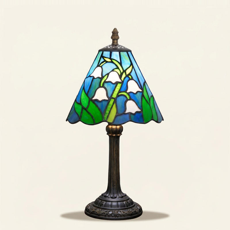 Muguette 8 Inch Tiffany-style stained glass table lamp, lit, on a plain ivory studio background