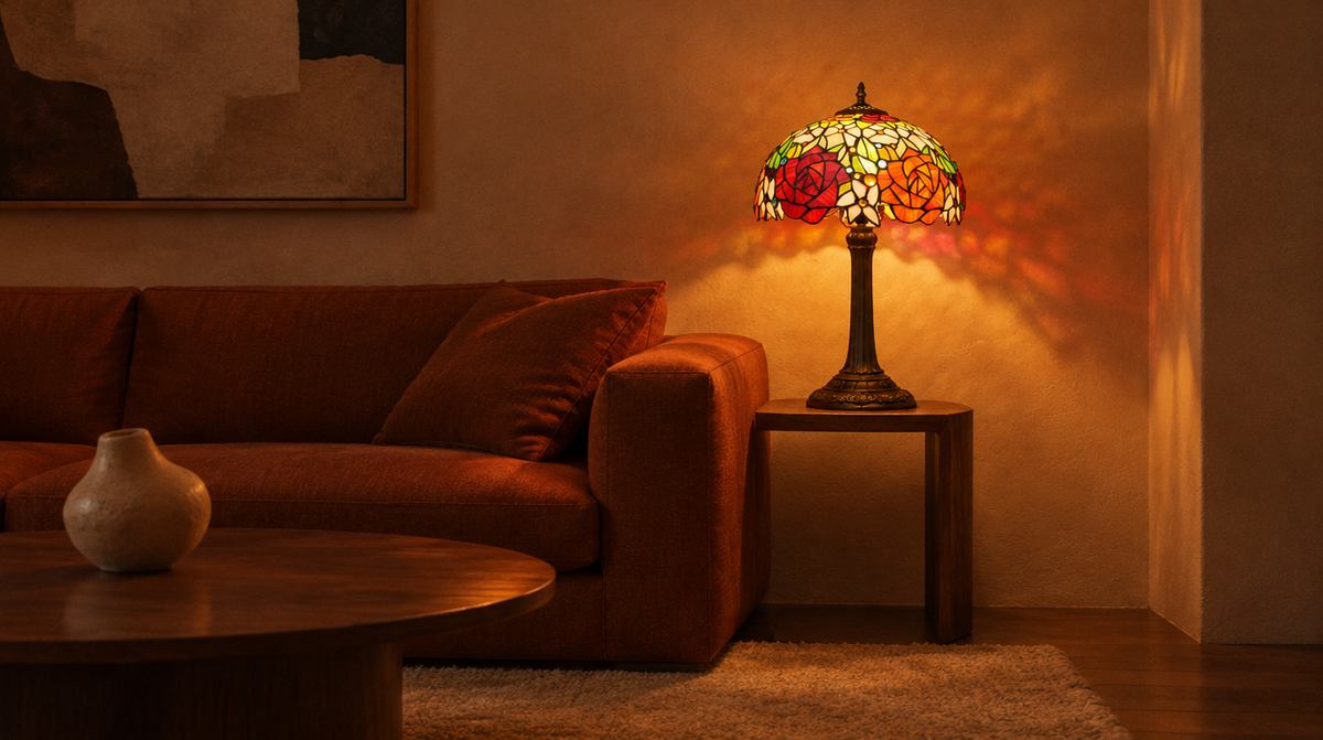 Rosalind 12 inch stained glass table lamp lit on a side table beside a rust linen sofa